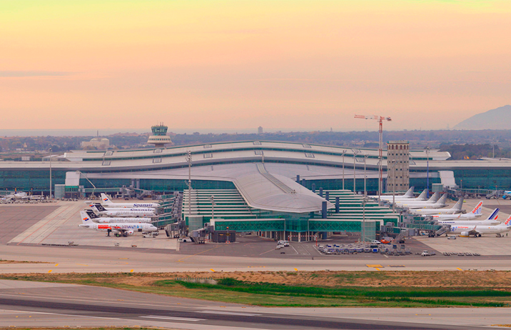 Trayecto desde el aeropuerto de Barcelona con vehículo de alta gama Aeropuerto de El Prat con aviones en pista al amanecer.