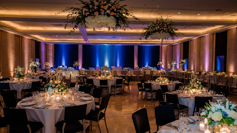 Salón decorado para celebración elegante con mesas iluminadas. Espacio ideal para bodas y eventos exclusivos