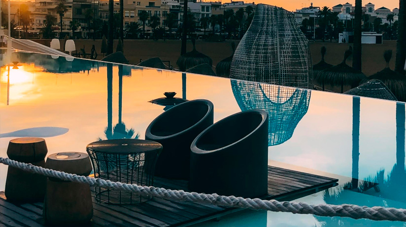 Terraza lounge en Ibiza con piscina y sillas modernas al atardecer. Espacios exclusivos ideales para relajarse tras un traslado en Ibiza.